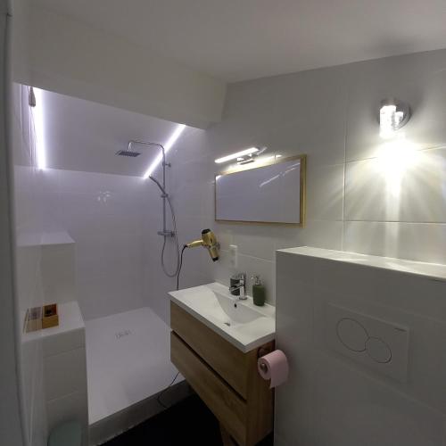 une salle de bain blanche avec un lavabo et un miroir dans l'établissement La Maunia Studio, à Montceaux