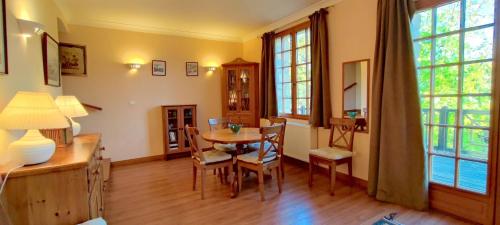 une salle à manger avec une table, des chaises et des fenêtres dans l'établissement La Maison au Bord du Lac, à Groléjac