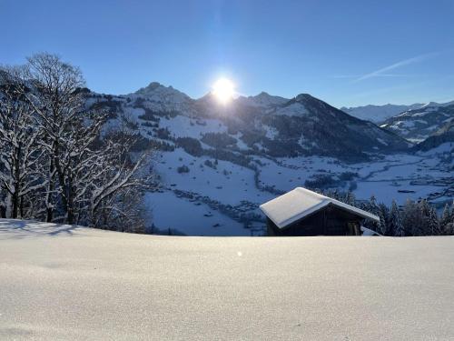 una montaña cubierta de nieve con el sol en el fondo en Apartment Heimersberg by Interhome, en Zweisimmen