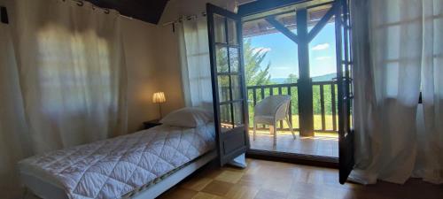 een slaapkamer met een bed en een deur naar een balkon bij La Tour de Véra in Auriac-du-Périgord