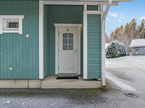 a green house with a white door on it at Holiday Home Kylpylän ullanrinne 12 d by Interhome in Ikaalinen