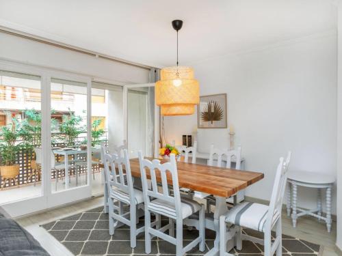 a dining room with a wooden table and white chairs at Apartment Serenity by Interhome in Tossa de Mar