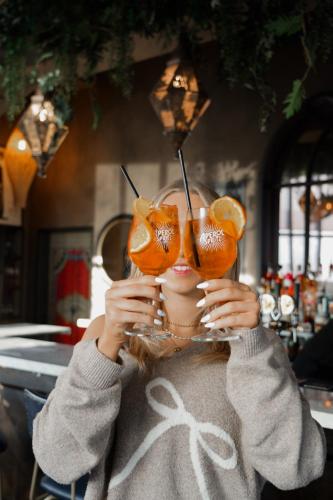 a woman is holding up a glass of orange juice at Nordic Hostel in Reykjavík