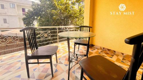 a glass table and two chairs on a balcony at StayMist - Ocean Lemon Pool Villa with Jacuzzi in Alibaug