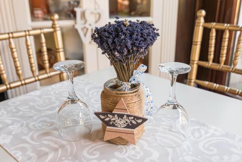 a table with two wine glasses and a vase with purple flowers at Casa del Sole Boutique Hotel Timisoara in Timişoara