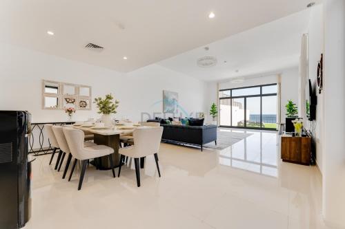 a dining room and living room with a table and chairs at Gulf and Mountain Views 4BR Villa with Assistant Room on Al Dana Island Fujairah by Deluxe Holiday Homes in Fujairah