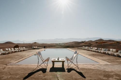 two chairs and a table in front of a pool at Alkamar Camp Agafay in El Karia