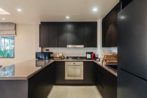 a kitchen with black cabinets and a black refrigerator at Barcelo Coconut Island, Phuket in Phuket Town