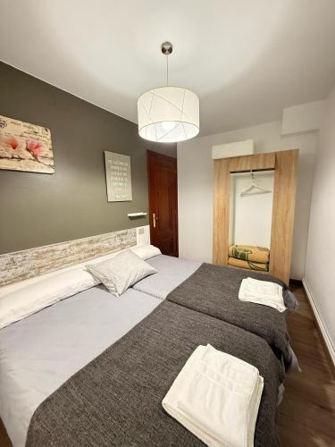 a bedroom with two beds and a mirror at Apartamentos Portolux in Portomarin