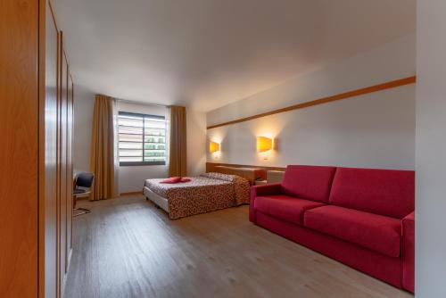 salon z czerwoną kanapą i łóżkiem w obiekcie Bonotto Hotel Palladio w mieście Bassano del Grappa