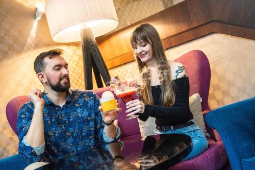 a man and a woman sitting in a chair with drinks at Primavera Jastrzębia Góra in Jastrzębia Góra