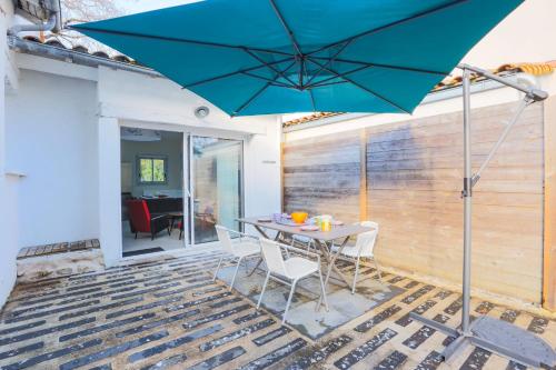 une terrasse avec une table et un parasol bleu dans l'établissement Maison Fantasio - Welkeys, à Dolus-d'Oléron
