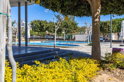a pool in a park with yellow flowers at Olga Premium Apartments in Limassol