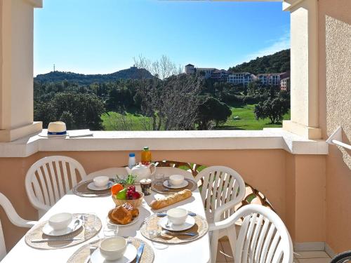 une table blanche avec des chaises et de la nourriture sur un balcon dans l'établissement Apartment Village Cap Estérel - L'Esquinade-111 by Interhome, à Agay