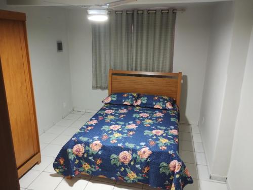 a bedroom with a bed with a floral comforter at Casa em Itapoá in Vila Velha