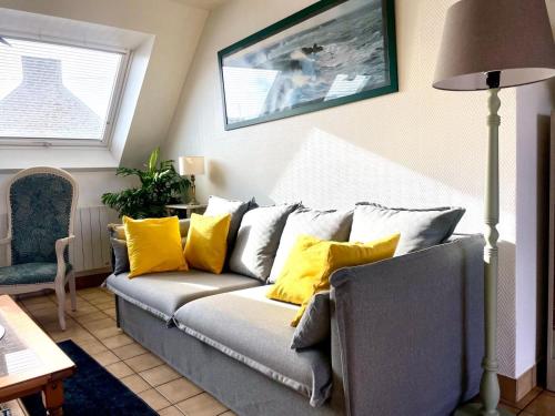 - un salon avec un canapé gris et des oreillers jaunes dans l'établissement Maison de la plage Santec, à Santec