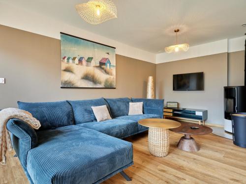 un salon avec un canapé bleu et une table dans l'établissement Holiday Home L'Aventure Gouvillaise by Interhome, à Gouville-sur-Mer