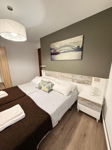 a bedroom with a bed and a painting on the wall at Apartamentos Portolux in Portomarin