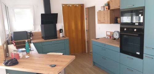 une cuisine avec des placards bleus et une table en bois dans l'établissement Maison Le Fenouiller Vendée 8 personnes 3 étoiles, à Le Fenouiller