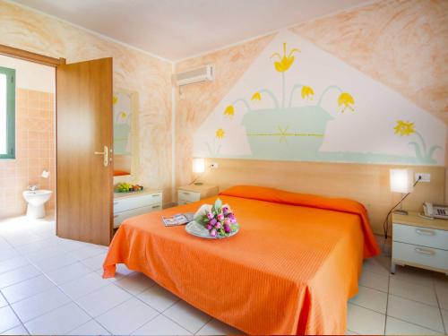 a bedroom with a bed with a bowl of flowers on it at Hotel Ariadimari in Valledoria