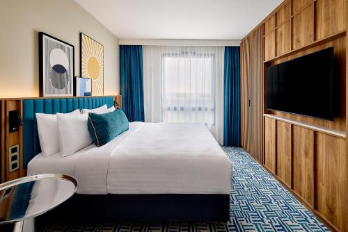 a hotel room with a large bed and a flat screen tv at Courtyard by Marriott Lyon Eurexpo Stadium in Genas