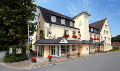 un grande edificio bianco con fiori rossi di fronte di Hotel Lindenhof a Warstein