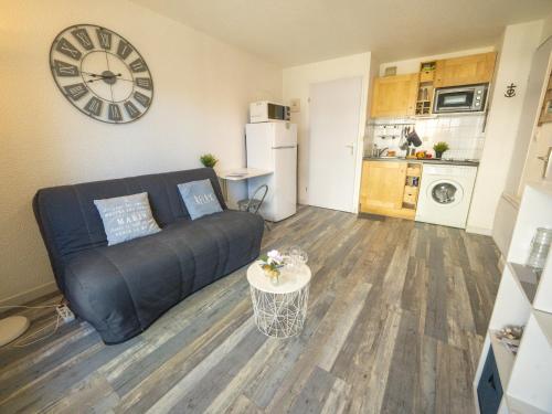 un salon avec un canapé et une horloge au mur dans l'établissement Apartment Les Terrasses du Lac-10 by Interhome, au Grau-du-Roi