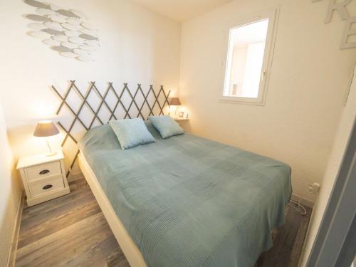 une chambre avec un lit avec des draps bleus et une fenêtre dans l'établissement Apartment Les Terrasses du Lac-10 by Interhome, au Grau-du-Roi