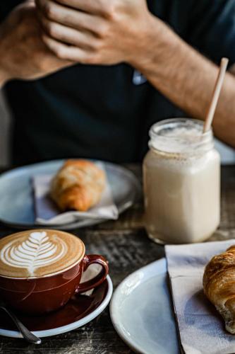 a person sitting at a table with a cup of coffee and pastries at The Lubo - self check-in in Luzern