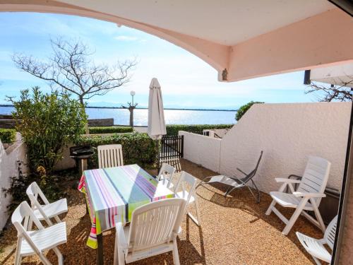 une terrasse avec des chaises blanches, une table et un parasol dans l'établissement Apartment Grenade-1 by Interhome, au Barcarès