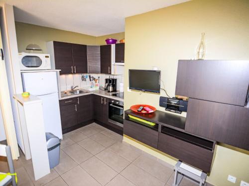 La cuisine est équipée de placards bruns et d'un réfrigérateur blanc. dans l'établissement Apartment Grenade-1 by Interhome, au Barcarès