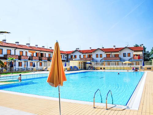 a swimming pool with an orange umbrella and some buildings at Apartment Solmare-52 by Interhome in Rosapineta