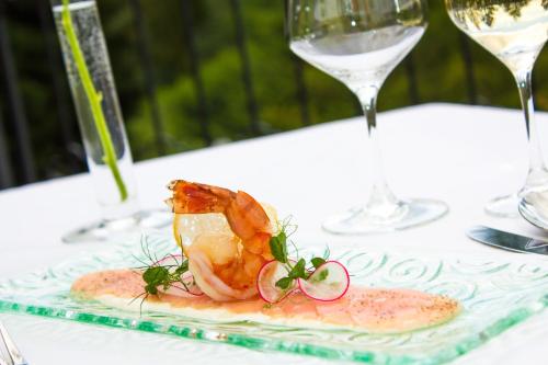 a plate of food with shrimp on a table with wine glasses at Schlosshotel Rosenau Superior in Schloss Rosenau