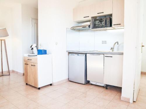 une cuisine blanche avec un évier et un micro-ondes dans l'établissement Apartment Les Rives Latines-3 by Interhome, à Fréjus