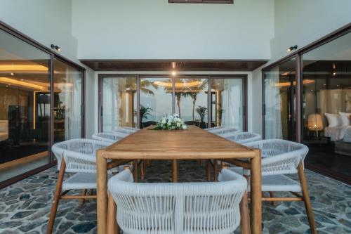 a dining room with a wooden table and white chairs at Barcelo Coconut Island, Phuket in Phuket Town