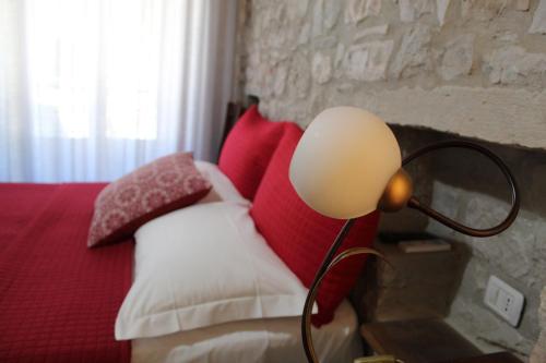 a lamp sitting next to a bed with red and white pillows at Affittacamere Al Piano in Trivento