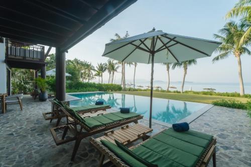 a pool with two lounge chairs and an umbrella at Barcelo Coconut Island, Phuket in Phuket Town