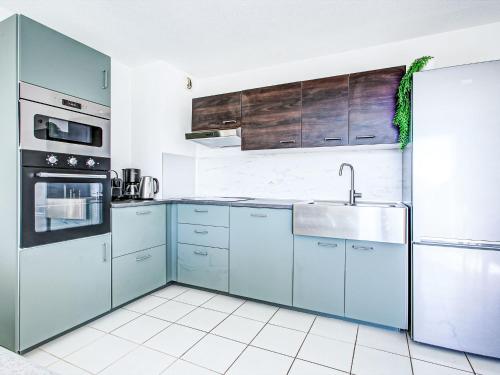 une cuisine avec des armoires bleues et un évier dans l'établissement Apartment Malibu Village by Interhome, à Canet