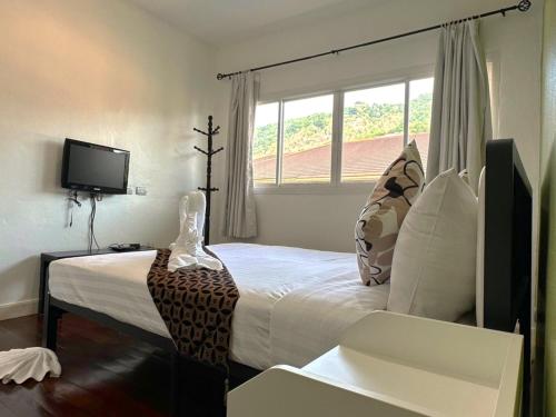 a bedroom with a large bed with a window at Sea Boss Homestay in Kata Beach