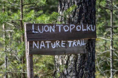 a sign hanging on a tree in front of a tree at Hotel Korpilampi in Espoo