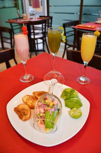a plate of food on a red table with two drinks at Hotel Del Rio in Constitución