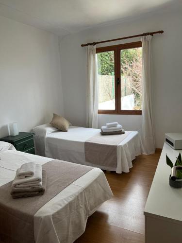 a white room with two beds and a window at Villa Aire in Cala en Blanes