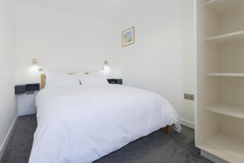 a white bedroom with a white bed and shelves at Pitts Cottage Annexe in Bladon