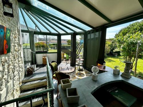 - une véranda avec une baignoire dans une chambre dotée de fenêtres dans l'établissement Tout Arrive ! - Située sur le Chenal de la Grève, à La Tremblade