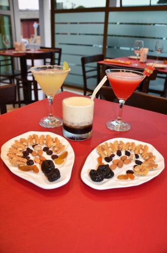 two plates of food on a red table with drinks at Hotel Del Rio in Constitución