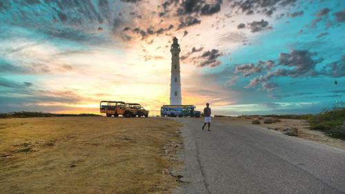 a man walking down a road in front of a lighthouse at Safir 40 in Palm-Eagle Beach