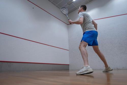 a man swinging a tennis racket in a tennis court at Hotel Korpilampi in Espoo
