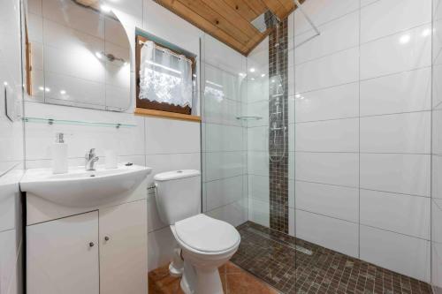 a white bathroom with a toilet and a sink at Domki letniskowe Ranczo in Darłowo