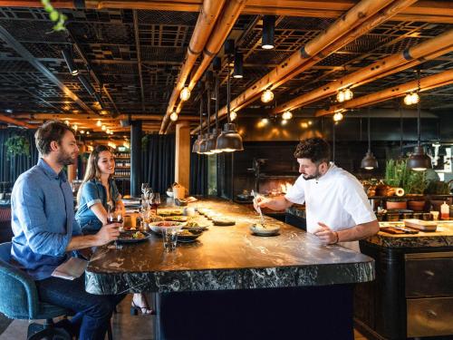 a group of people sitting around a bar in a restaurant at Novotel Istanbul Bosphorus Hotel in Istanbul