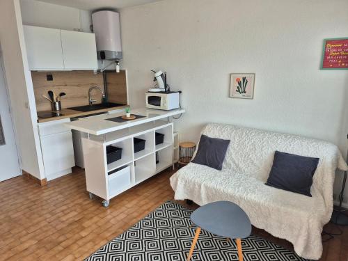 un salon avec un canapé et une cuisine dans l'établissement La Désirade J, Studio rénové avec parking, centre port, au Cap d'Agde